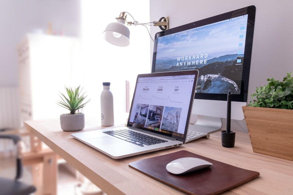 Composition of a camera and coffee cup next to a desk with an open laptop
