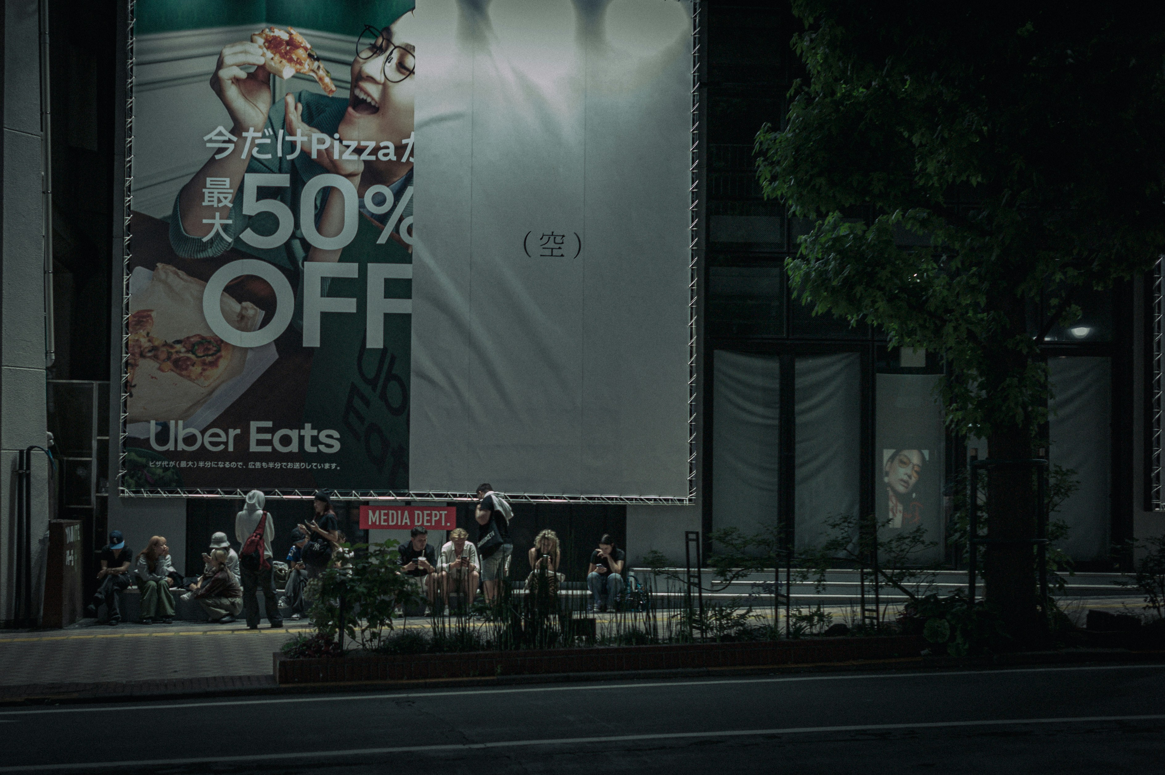 スマホに映るSNSの広告画面と、横にマーケティング用の資料が広げられているシーン